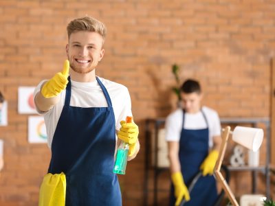Male janitor showing thumb-up gesture in office during cleaning
